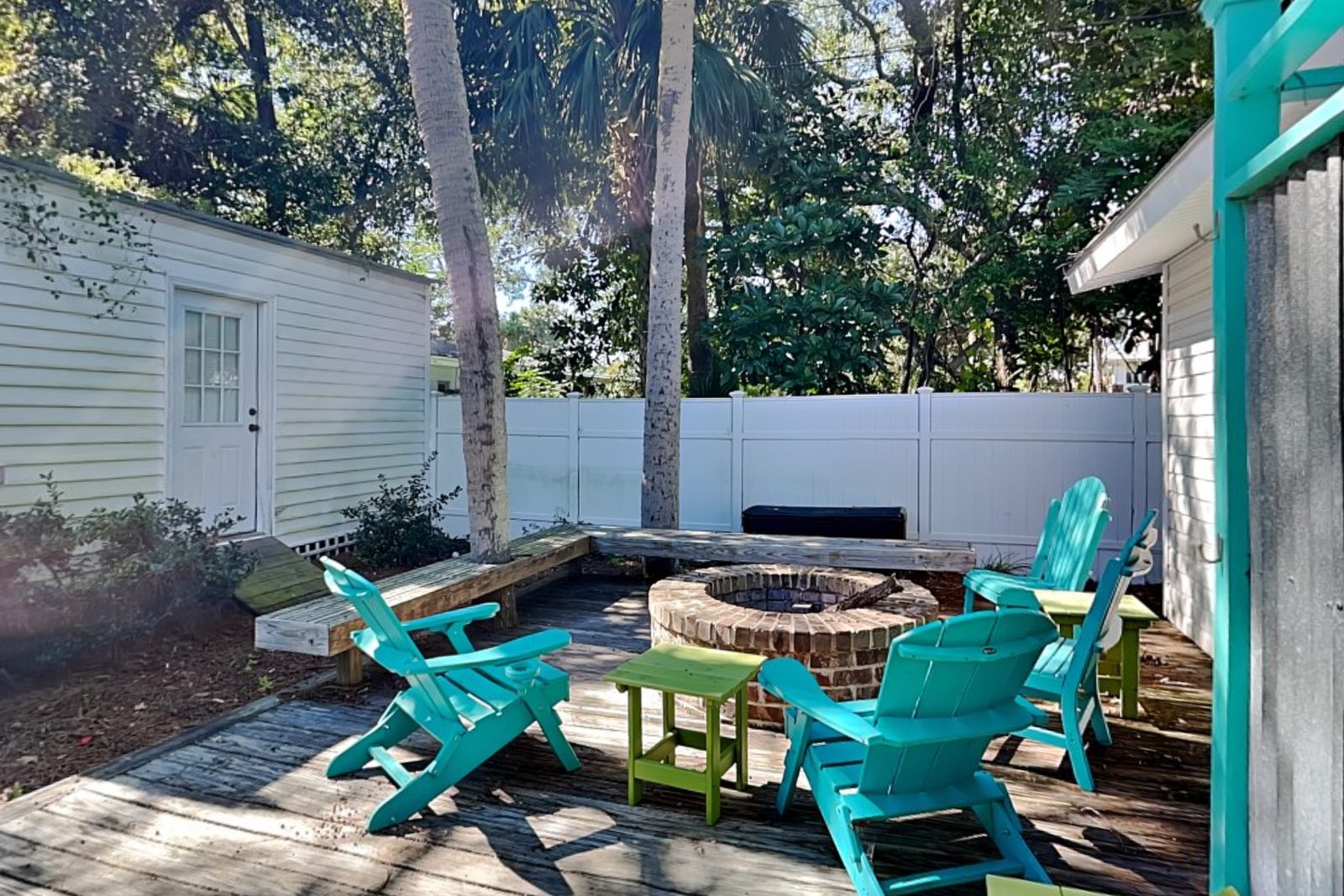 Back deck with a brick fire pit ringed by turquoise Adirondack chairs